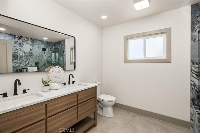 bathroom with double vanity, a stall shower, a sink, and toilet