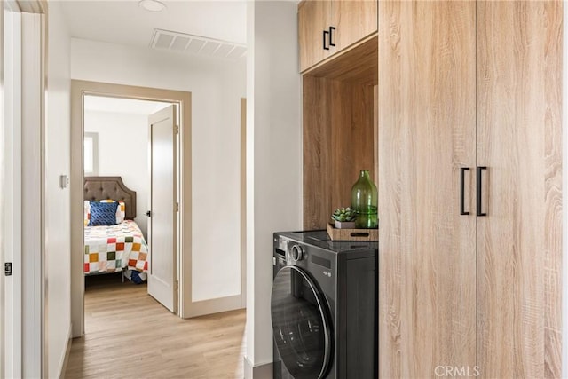 laundry area with washer / dryer, laundry area, visible vents, baseboards, and light wood-style flooring