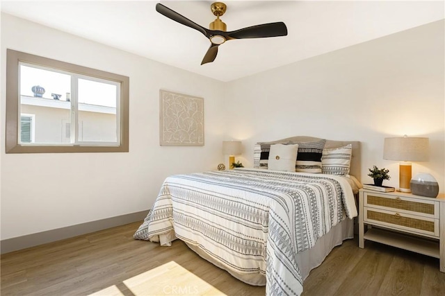 bedroom with a ceiling fan, baseboards, and wood finished floors