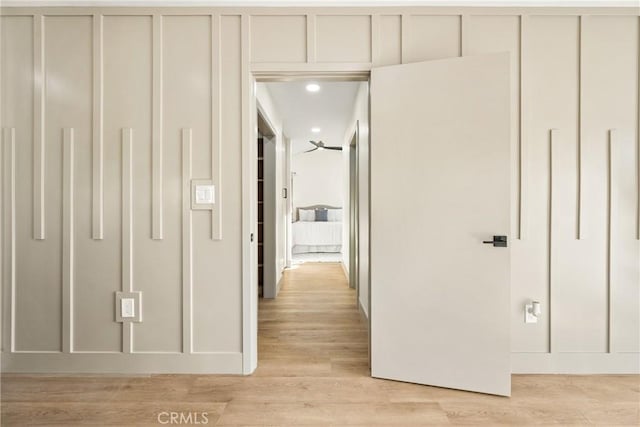 hallway featuring light wood-type flooring and a decorative wall