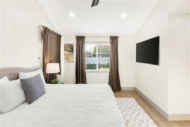 bedroom with vaulted ceiling, light wood-style flooring, and baseboards