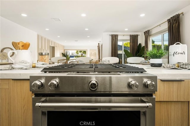 kitchen with high end stainless steel range oven, modern cabinets, light countertops, and light brown cabinetry