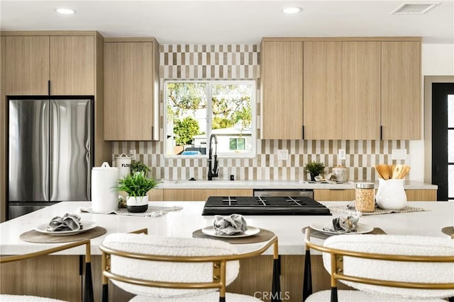 kitchen featuring visible vents, light countertops, tasteful backsplash, and freestanding refrigerator