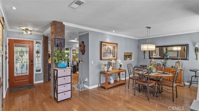 dining area with an inviting chandelier, hardwood / wood-style floors, crown molding, and a textured ceiling