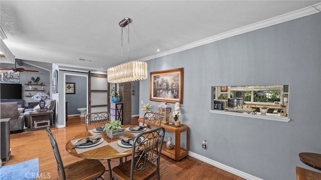 dining room featuring a barn door, ceiling fan with notable chandelier, crown molding, and hardwood / wood-style floors