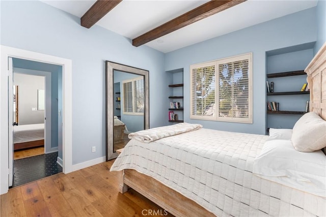 bedroom featuring beamed ceiling and light hardwood / wood-style floors