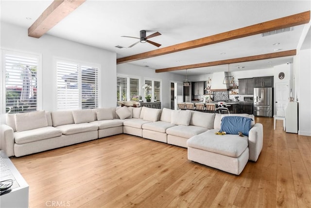 living room with plenty of natural light, light hardwood / wood-style flooring, and beamed ceiling