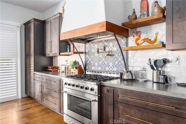 kitchen featuring high end stainless steel range, backsplash, dark brown cabinets, and custom range hood