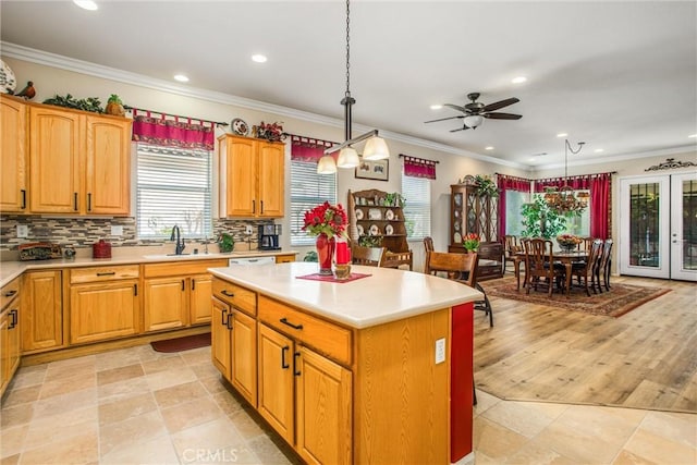 kitchen with ceiling fan, pendant lighting, a kitchen island, sink, and ornamental molding