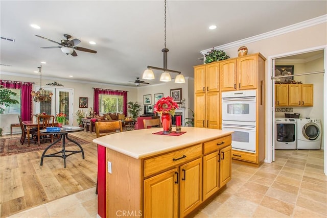 kitchen featuring a center island, pendant lighting, white double oven, separate washer and dryer, and ornamental molding