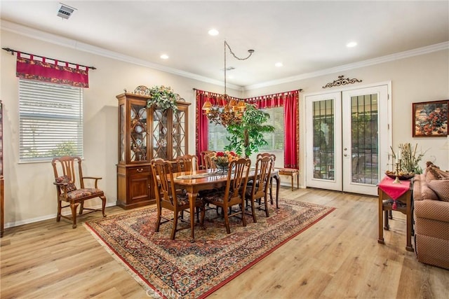 dining area featuring an inviting chandelier, ornamental molding, light hardwood / wood-style floors, and french doors