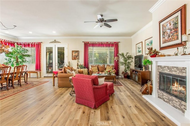 living room with light wood-type flooring, a brick fireplace, plenty of natural light, and ceiling fan