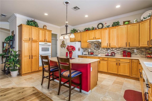 kitchen featuring white appliances, a kitchen island, hanging light fixtures, a breakfast bar, and crown molding