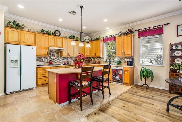 kitchen featuring wine cooler, pendant lighting, a center island, a breakfast bar, and white fridge with ice dispenser