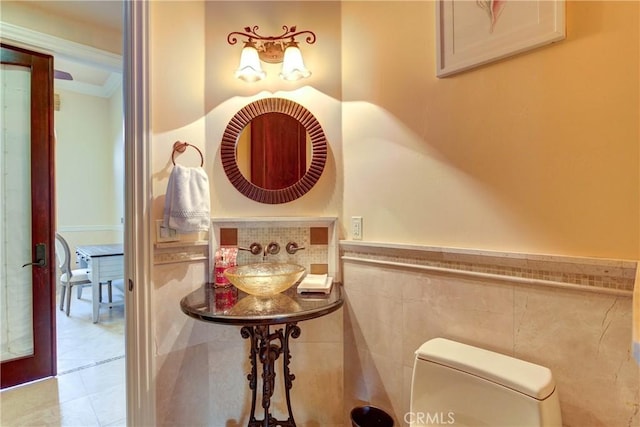 bathroom with toilet, tile patterned flooring, tile walls, and sink