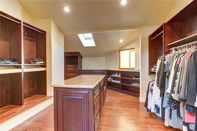 spacious closet featuring light hardwood / wood-style floors and vaulted ceiling with skylight