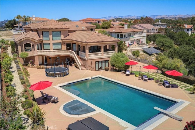 view of pool featuring a diving board, a trampoline, a patio area, and a mountain view