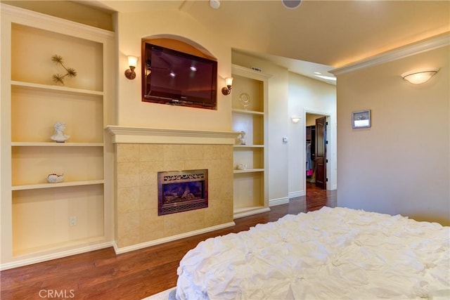 bedroom with a tiled fireplace and dark wood-type flooring