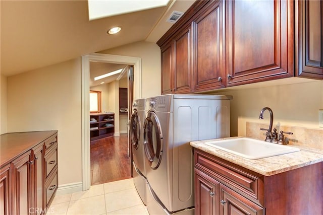 laundry room with light tile patterned flooring, cabinets, washer and dryer, and sink