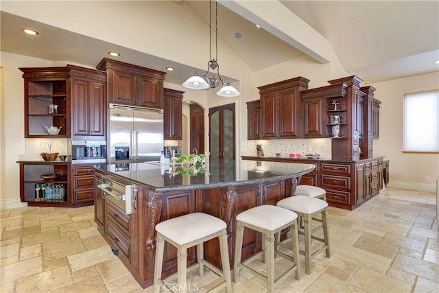 kitchen featuring a kitchen island, decorative light fixtures, stainless steel appliances, backsplash, and a breakfast bar