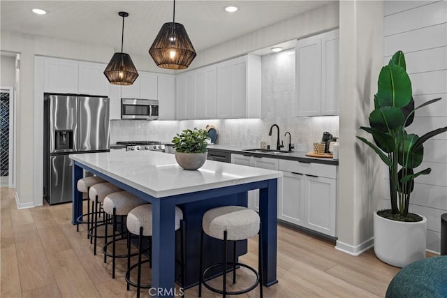 kitchen with decorative light fixtures, white cabinets, appliances with stainless steel finishes, and sink