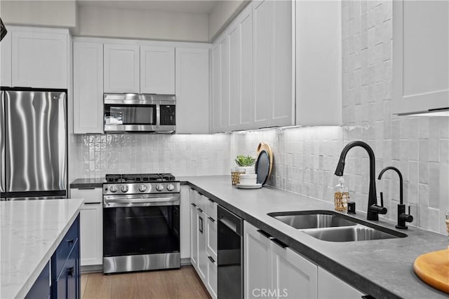 kitchen featuring stainless steel appliances, backsplash, white cabinets, and sink