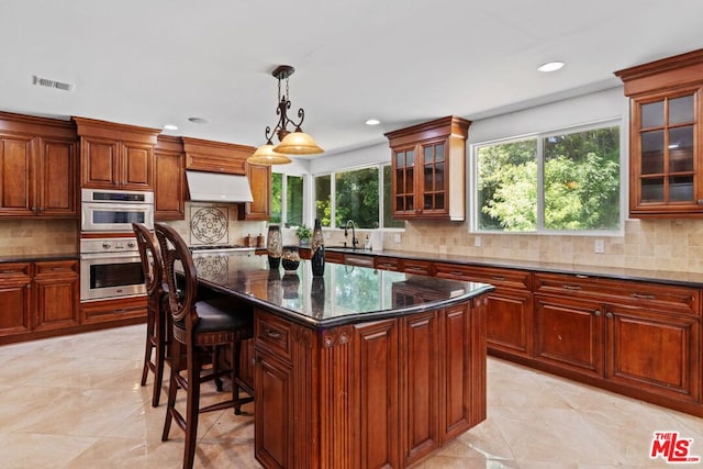 kitchen featuring tasteful backsplash, dark stone counters, pendant lighting, and a center island