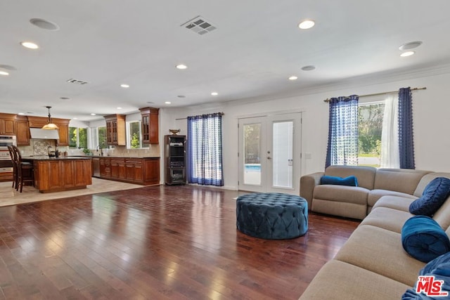 living room featuring dark hardwood / wood-style flooring, crown molding, and french doors