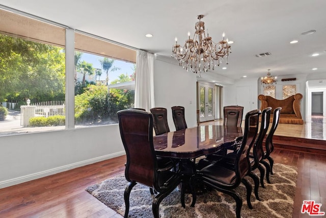 dining space with wood-type flooring, a wealth of natural light, and a chandelier