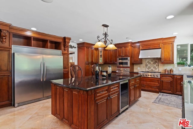 kitchen with ventilation hood, appliances with stainless steel finishes, decorative light fixtures, wine cooler, and a center island