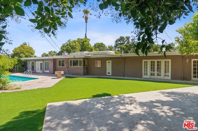 rear view of house featuring a lawn, french doors, and a patio