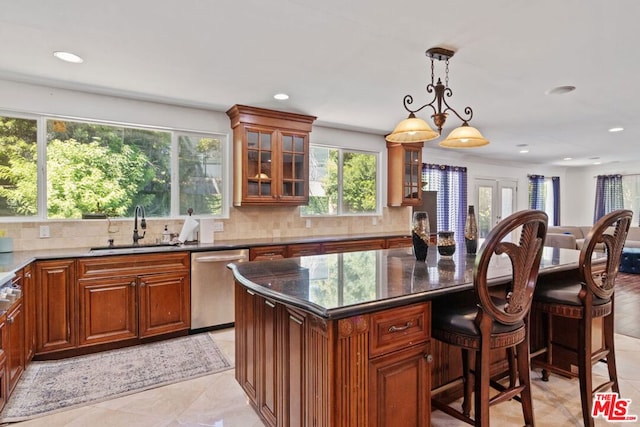 kitchen with pendant lighting, stainless steel dishwasher, a kitchen island, a kitchen bar, and sink