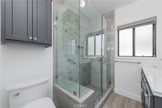 bathroom with toilet, hardwood / wood-style flooring, a shower with door, and vanity