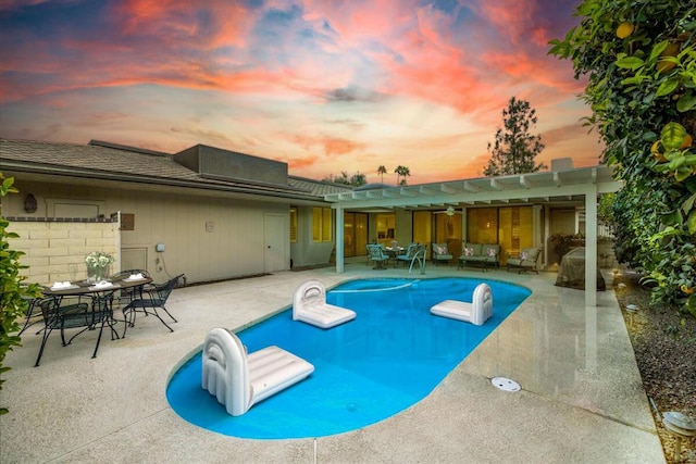 pool at dusk with a patio area