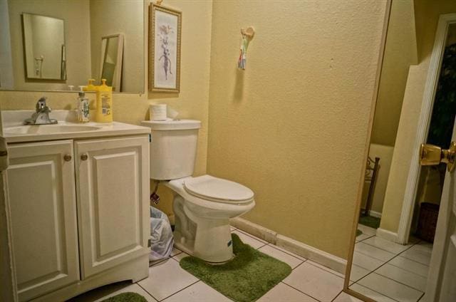 bathroom with toilet, tile patterned flooring, and vanity