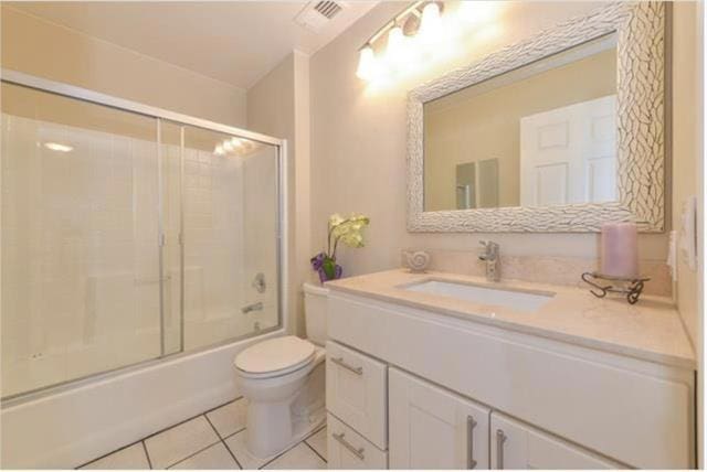 full bathroom with tile patterned floors, enclosed tub / shower combo, vanity, and toilet