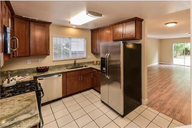 kitchen with light stone counters, sink, appliances with stainless steel finishes, and light tile patterned floors