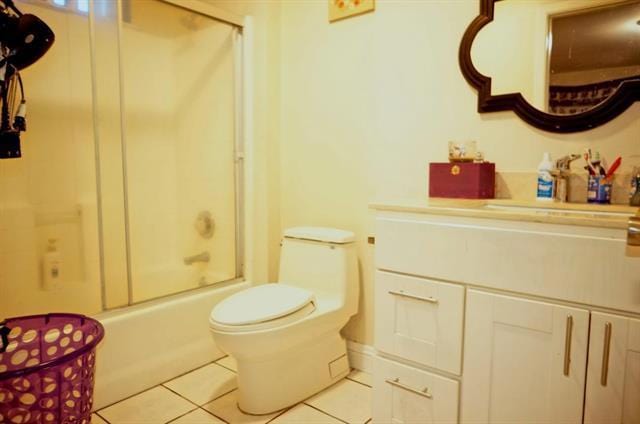 full bathroom with toilet, tile patterned flooring, vanity, and shower / bath combination with glass door