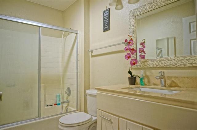 full bathroom with shower / bath combination with glass door, vanity, and toilet