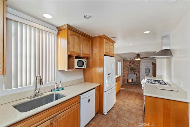 kitchen with white appliances, sink, ventilation hood, a brick fireplace, and light tile patterned floors