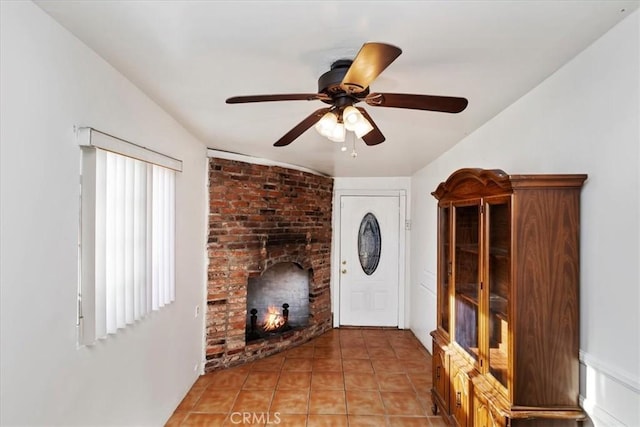 foyer entrance featuring ceiling fan, light tile patterned flooring, vaulted ceiling, and a brick fireplace