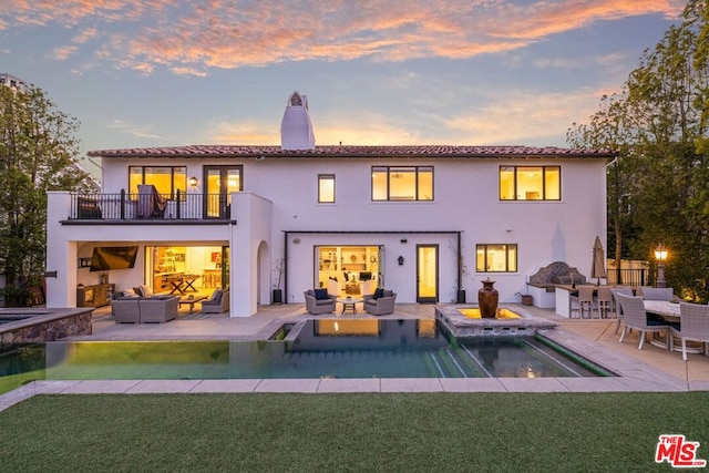 back of house featuring a pool with hot tub, a lawn, a patio area, outdoor lounge area, and a balcony