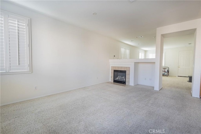 unfurnished living room with light colored carpet and a tiled fireplace