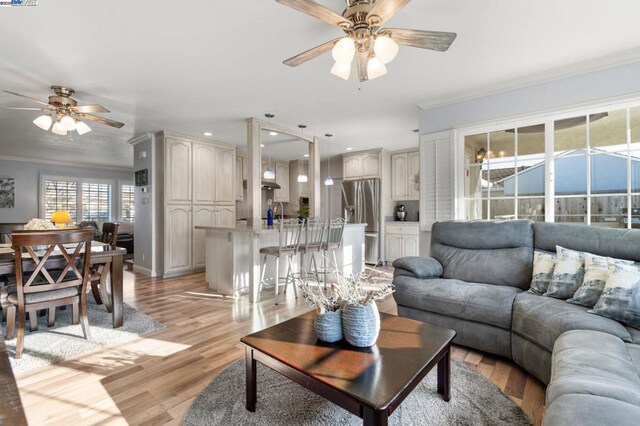 living room with ceiling fan, ornamental molding, and light hardwood / wood-style floors