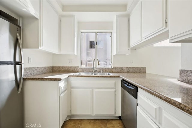 kitchen with stone counters, sink, light tile patterned floors, stainless steel appliances, and white cabinets