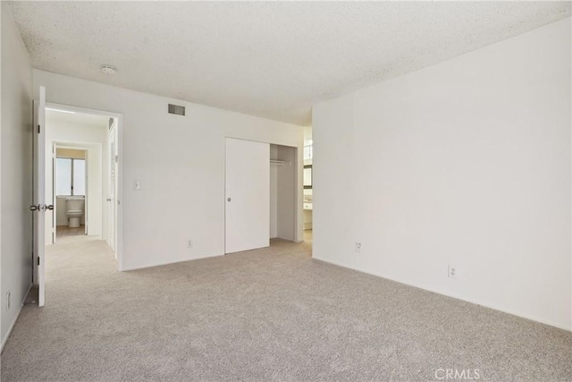 unfurnished bedroom with light colored carpet, a textured ceiling, and a closet