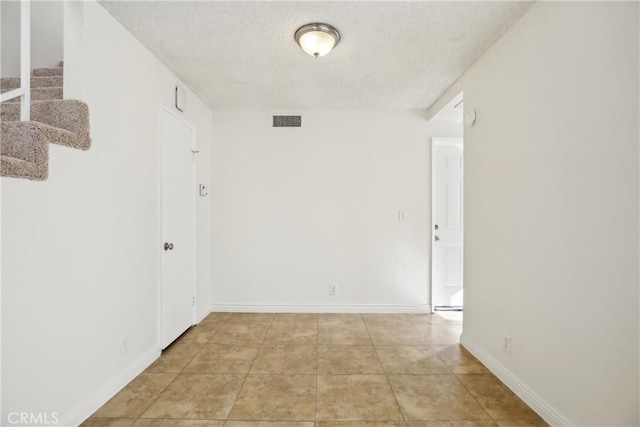 tiled empty room with a textured ceiling