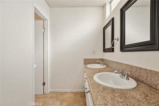 bathroom with a textured ceiling, tile patterned flooring, and vanity