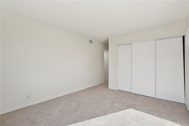 unfurnished bedroom featuring light carpet and a closet