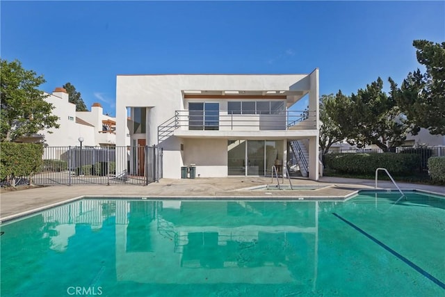 rear view of property with a patio area, a community pool, and a balcony